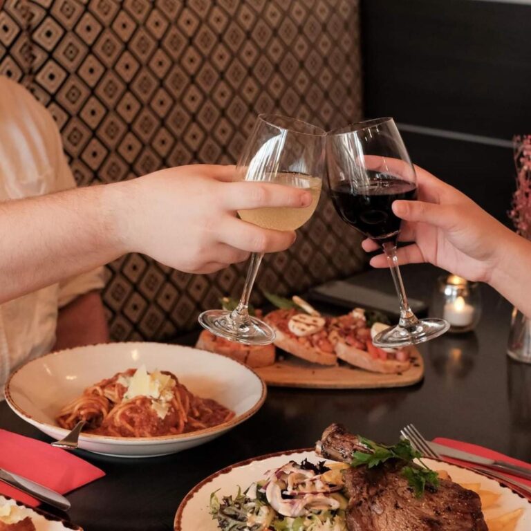 Two glasses clinking over a dinner table.