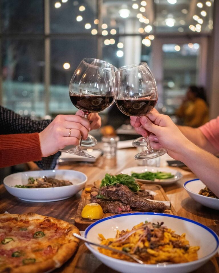 Cheers with wine glasses over a dinner table.